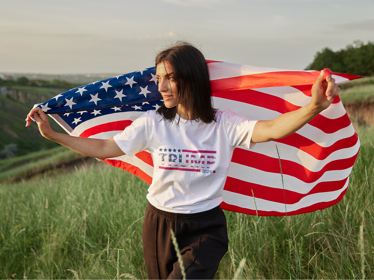 Person holding an American flag in a field
